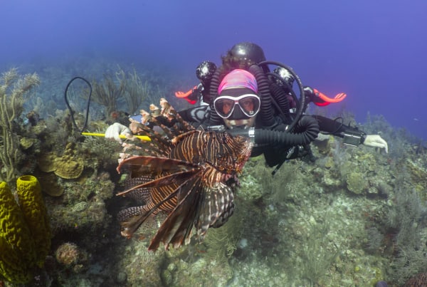 Diver with red lionfish underwater