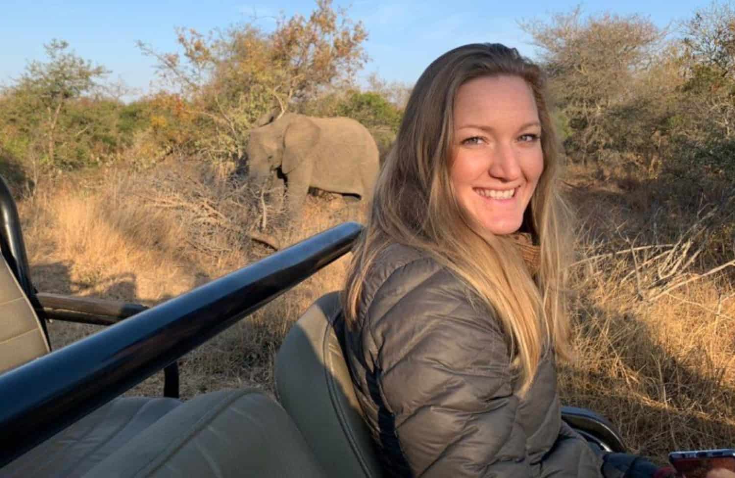 Photo of a girl in an outdoor safari with an elephant behind her